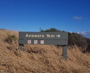 Location sign on a hill that reads "Answers 1 km"