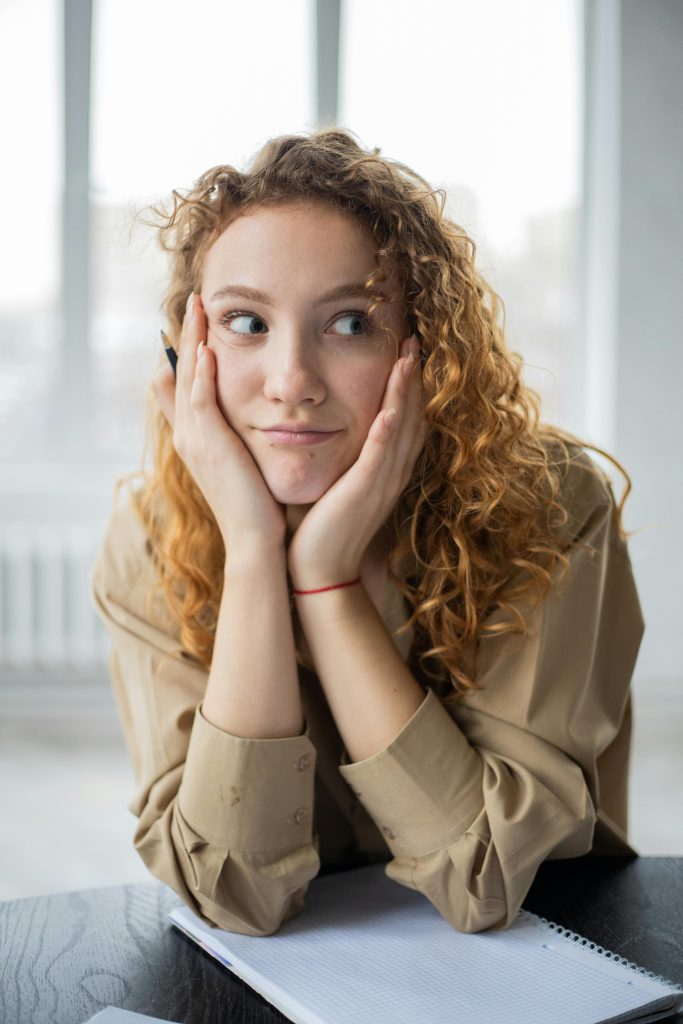 Figure 6.5: Image of woman with hands on face looking away. Sometimes we are distracted with our own thoughts and judgments instead of focusing on the speaker.