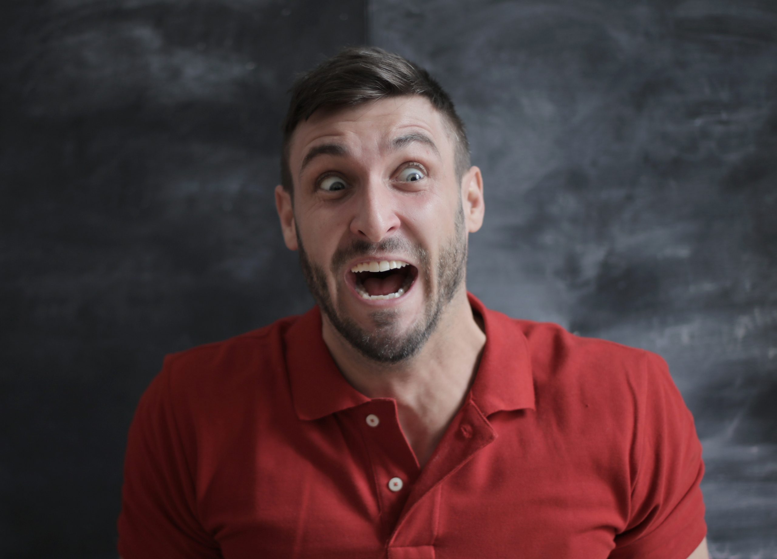 Photograph of a man with raised eyebrows, open mouth, and a half smile.