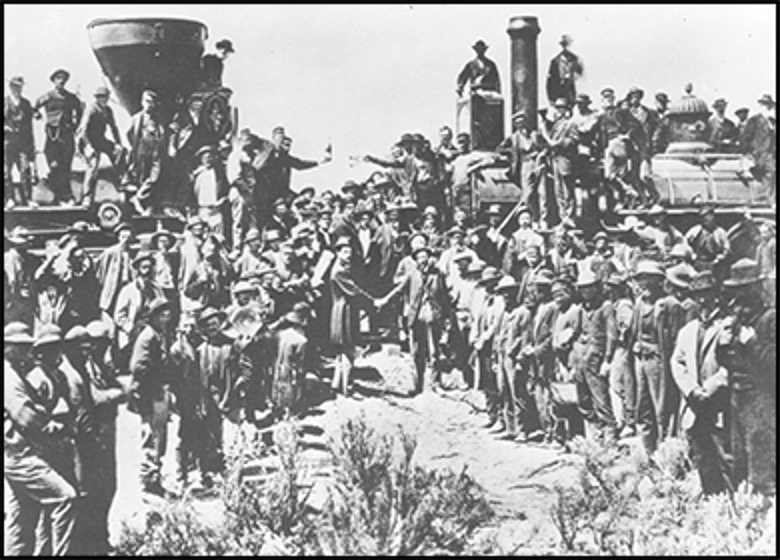 Photo of two railroad engines facing each other and a crowd surrounding two men shaking hands where the transcontinental east and west lines met.