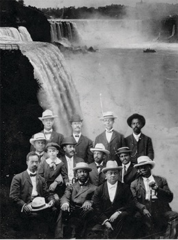 Photograph of W. E. B. DuBois and other men in three rows. The men in the first two rows are seated. DuBois is in the second row.
