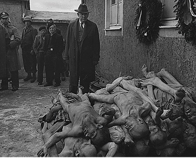 A black and white photograph of American officials touring Buchenwald concentration camp and viewing the bodies of dead Jewish victims left exposed by the Germans.