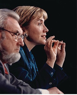 Close-up profile view of Hillary Clinton speaking, with C. Everett Koop in the foreground.